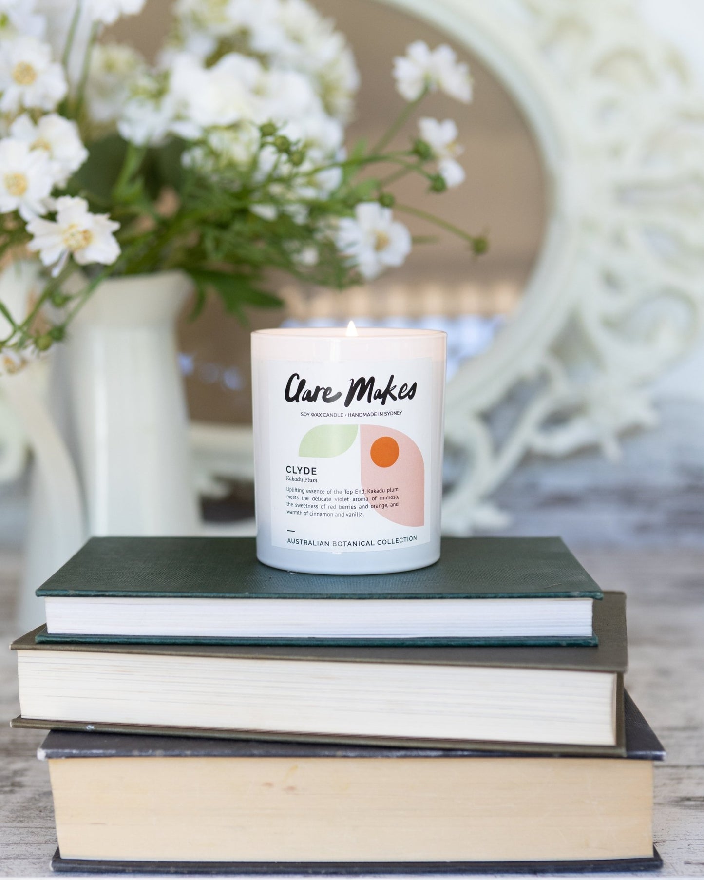 Clare Makes Clyde candle in sweet fruity Kakadu Plum scent stacked on books