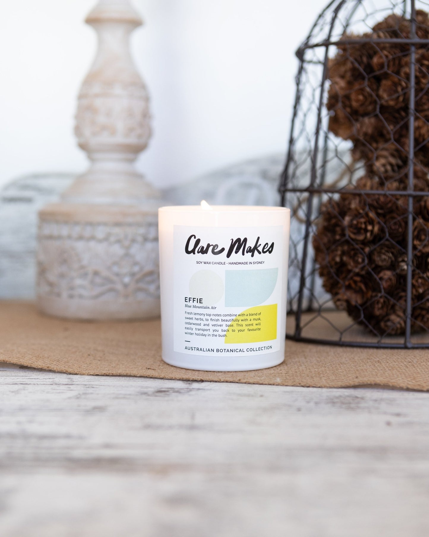 Effie: Blue Mountain Air candle styled on white timber with pinecones and eucalyptus