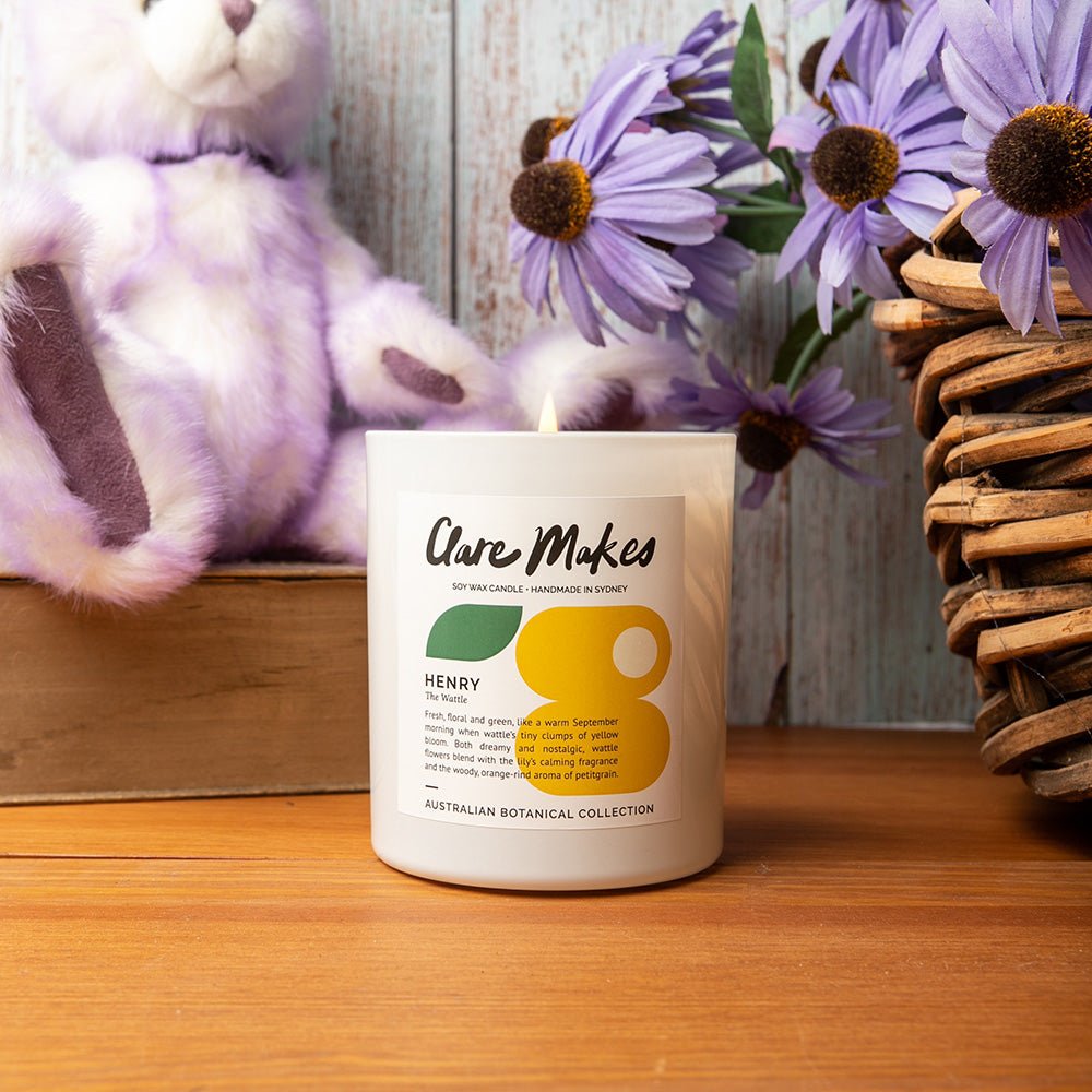 Clare Makes Henry candle with wattle scent, styled with purple blooms for a soft Australian floral vibe