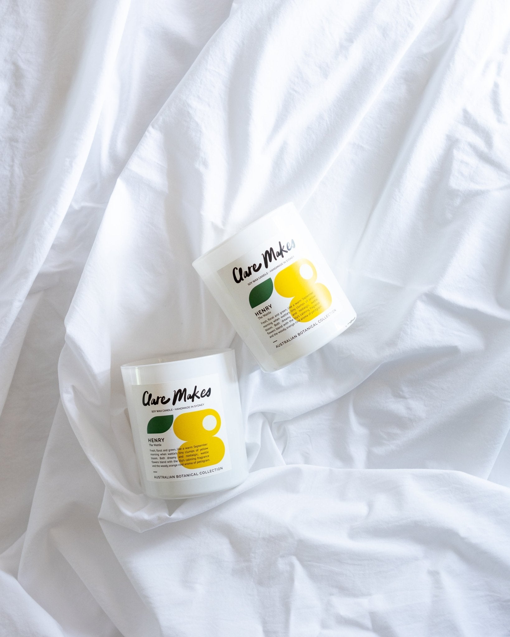 Clare Makes Henry candle on white sheets, styled for a fresh and minimalist bedroom look
