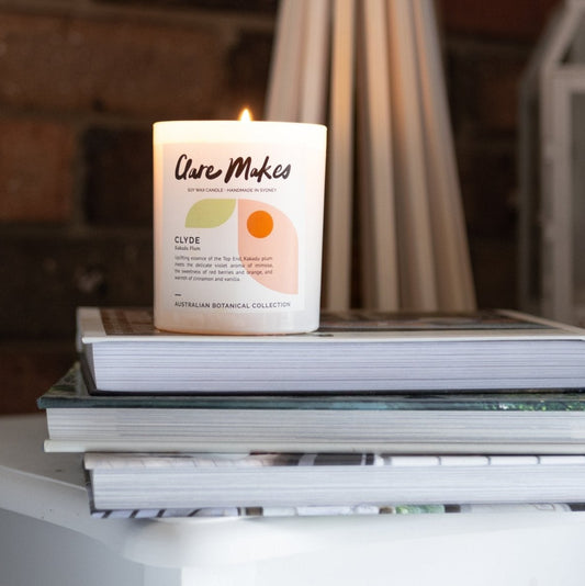 Clare Makes Clyde candle in sweet fruity Kakadu Plum scent stacked on books